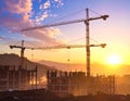 Sunset illuminates a construction site with two tall tower cranes Royalty Free Stock Photo