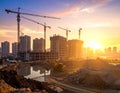 Construction site during a sunset with multiple cranes and half-built structures Royalty Free Stock Photo