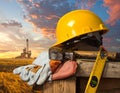 Yellow hard hat, hammer, work gloves, and measuring tape on wooden surface in foreground Royalty Free Stock Photo