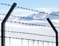 A barbed wire fence with three strands is seen up close, framed by metal posts Royalty Free Stock Photo