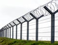 Barbed wire security fence with multiple horizontal strands supported by concrete posts Royalty Free Stock Photo