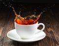 Cup of tea with splash on dark wooden background Royalty Free Stock Photo