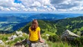 Woman hiker sits and enjoys valley view from viewpoint. Hiker reached top of the moun Royalty Free Stock Photo