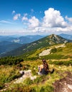 Woman hiker sits and enjoys valley view from viewpoint. Hiker reached top of the moun Royalty Free Stock Photo