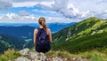 Woman hiker sits and enjoys valley view from viewpoint. Hiker reached top of the moun Royalty Free Stock Photo