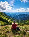 Woman hiker sits and enjoys valley view from viewpoint. Hiker reached top of the moun Royalty Free Stock Photo