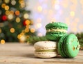 Beautifully decorated Christmas macarons on wooden table against blurred festive Royalty Free Stock Photo