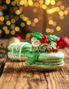 Beautifully decorated Christmas macarons on wooden table against blurred festive Royalty Free Stock Photo