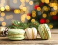 Beautifully decorated Christmas macarons on wooden table against blurred festive Royalty Free Stock Photo