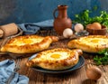 Delicious hachapuri filled with cheese and eggs, and a wooden table covered Royalty Free Stock Photo