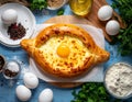 Delicious hachapuri filled with cheese and eggs, and a wooden table covered Royalty Free Stock Photo