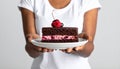 Woman holding plate with slice of chocolate sponge berry cake on grey background Royalty Free Stock Photo