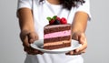 Woman holding plate with slice of chocolate sponge berry cake on grey background Royalty Free Stock Photo