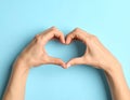 Woman making heart with her hands on light blue background, closeup Royalty Free Stock Photo