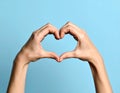 Woman making heart with her hands on light blue background, closeup Royalty Free Stock Photo