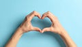 Woman making heart with her hands on light blue background, closeup Royalty Free Stock Photo