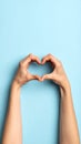 Woman making heart with her hands on light blue background, closeup Royalty Free Stock Photo