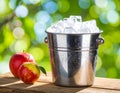 A shiny metal bucket filled with ice cubes sits on a wooden surface Royalty Free Stock Photo