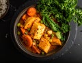 A bowl of vibrant vegetable curry includes diced tofu, carrot slices, peas, and corn Royalty Free Stock Photo
