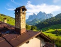 Rustic stone chimney on a sloped, brown metal roof, foreground Royalty Free Stock Photo
