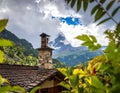 A rustic stone chimney rises from a wooden roof, framed by green leaves Royalty Free Stock Photo