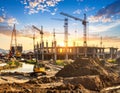 A construction site at sunset features multiple cranes and an unfinished multi-story building Royalty Free Stock Photo
