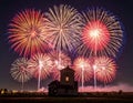 Vibrant fireworks illuminate the night sky with bursts of red, gold, blue, and white over a rural landscape Royalty Free Stock Photo