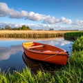 Outdoor photo of a dutch lake with reed collar behind it, orange dinghy without engin Royalty Free Stock Photo