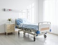 Hospital room featuring an adjustable bed with blue linens, placed on a light wooden floor Royalty Free Stock Photo