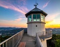White lighthouse with an octagonal glass top and conical roof sits on a hill Royalty Free Stock Photo