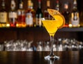 Yellow drink in champagne flut glass at the bar. There is an orange slice Royalty Free Stock Photo