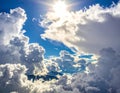 Bright sunlight filters through large, fluffy cumulus clouds against a vibrant blue sky Royalty Free Stock Photo