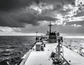 A naval vessel plows through the open sea under a dramatic sky Royalty Free Stock Photo