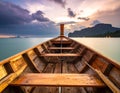 A wooden long-tail boat is seen from the inside, pointing toward a calm sea during sunset in Thailand Royalty Free Stock Photo
