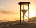 An hourglass is resting on sandy ground during sunset Royalty Free Stock Photo