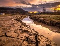 Sunset over a rural landscape featuring cracked clay soil, indicative of desiccation Royalty Free Stock Photo
