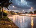 A city street slick with rain reflects warm streetlights against a backdrop of dark, stormy clouds Royalty Free Stock Photo