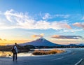 A person stands on a curved road gazing at Mount Fuji in Japan, under a sky brushed with clouds Royalty Free Stock Photo