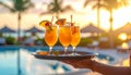 Generates the image of a hand holding a tray with tropical drinks and the hotel backg Royalty Free Stock Photo