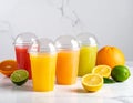 Plastic juice glasses and different citrus fruits on a white marble table, indoors Royalty Free Stock Photo