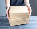 Woman holding empty cardboard boxes on a dark wooden background. Creating a model Royalty Free Stock Photo