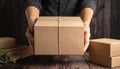 Woman holding empty cardboard boxes on a dark wooden background. Creating a model Royalty Free Stock Photo