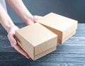 Woman holding empty cardboard boxes on a dark wooden background. Creating a model Royalty Free Stock Photo