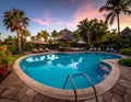 A serene poolside setting at sunset, featuring a circular swimming pool with a stone deck Royalty Free Stock Photo