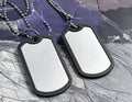 Two military dog tags with ball chains lie on a textured surface Royalty Free Stock Photo