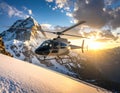 Helicopter flies over a snow-covered mountain landscape during sunset Royalty Free Stock Photo