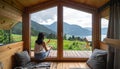 Woman sitting with a drink on terrace of tiny house in the mountains, view through Royalty Free Stock Photo