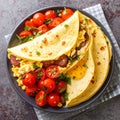 Close-up of a stack of tortillas with egg, sausage and tomatoes on a plate on a table Royalty Free Stock Photo