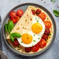 Close-up of a stack of tortillas with egg, sausage and tomatoes on a plate on a table Royalty Free Stock Photo