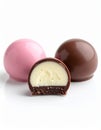Theree smooth glossy round pink, brown, white chocolate truffle balls, one cut open exposi Royalty Free Stock Photo